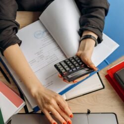 person holding black calculator while using laptop