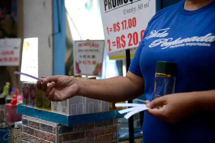 Vendedora entrega fragrâncias aos pedestres em loja na tradicional área de compras do Saara, no centro do Rio de Janeiro