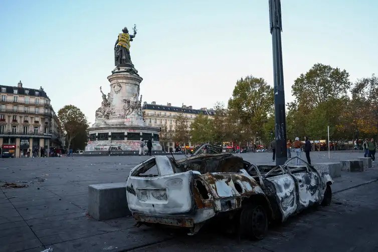 A destroyed car near the Marianne statue at the Place de la Republique, with a yellow vest put on it, the day after clashes during a national day of demonstrations against the cost of living and rising fuel prices, in Paris, France, October 18, 2026. The back of the vest reads: 'In 1961 the police drowns Algerian women'. REUTERS/Abdul Saboor     TPX IMAGES OF THE DAY